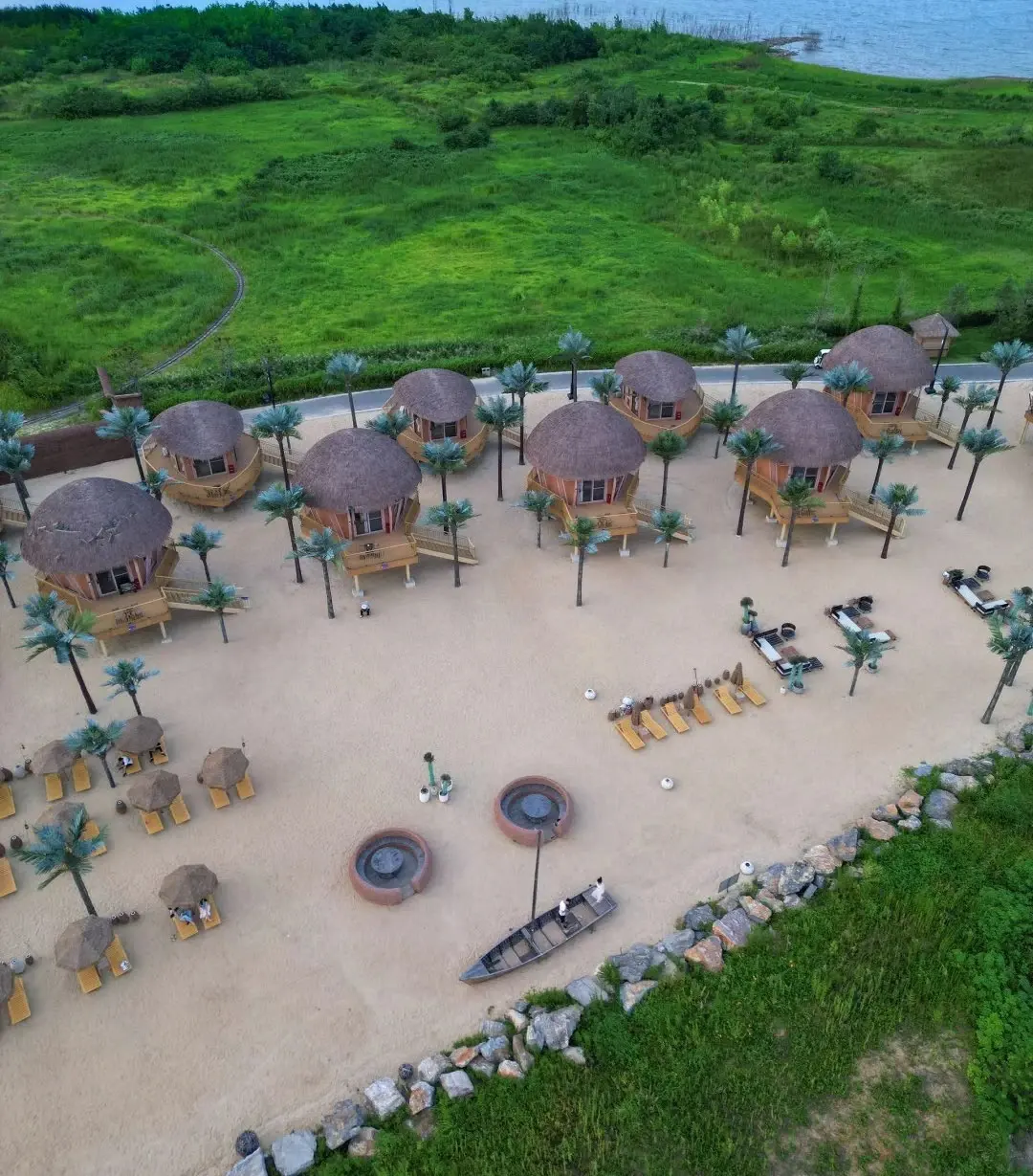 Aerial view of compact round guest cabins arranged around a landscaped waterfront setting